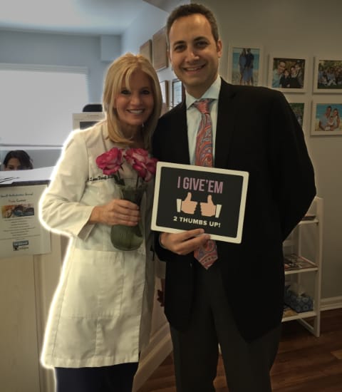 Dr. Danoff standing with man in tuxedo holding a sign that says I Give'em 2 thumbs up