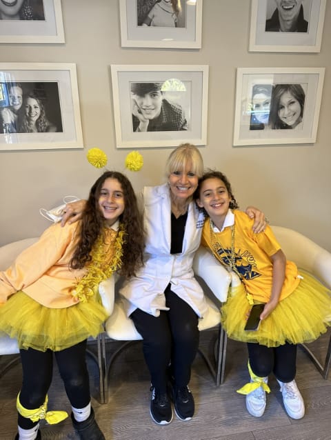 Dr. Danoff sitting in between two girls dressed as bees